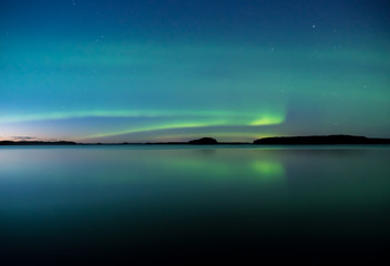 Northern lights dancing over calm lake in Farnebofjarden national park in Sweden