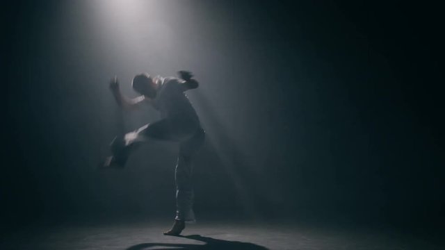 Man practicing capoeira in dark room. Slow motion