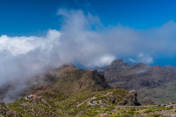 Lavalandschaft des Teno-Gebirges auf Teneriffa mit einer Serpentine-Straße unterm Wolkenteppich