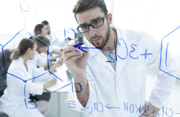 from behind the glass.scientist writes a marker on a glass Board.