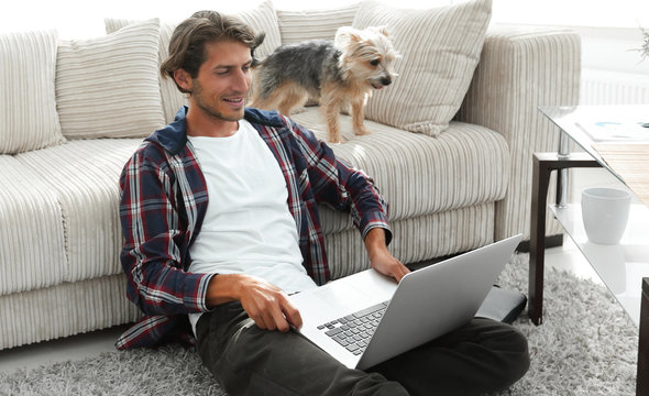 happy young man exults with his dog sitting in the living room