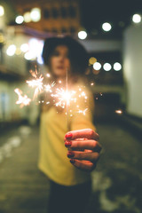 A young girl's hand holding lighter burning Christmas sparkler - obrazy, fototapety, plakaty