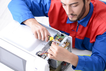 Young repairman fixing and repairing microwave oven