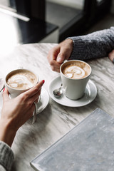 Female and man hands with cups of coffee on the background of a wooden table - 185147457