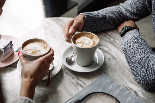 Female And Man Hands With Cups Of Coffee On The Background Of A Wooden Table