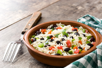 Traditional cuban rice, black beans and pepper on wooden table background. Moros y cristianos.