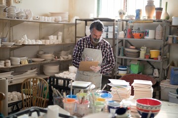Fototapeta na wymiar Male potter maintaining record on clipboard