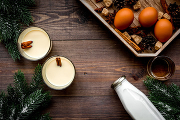 Ingredients for eggnog. Eggs, milk, cinnamon, whiskey on dark wooden background top view
