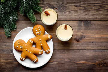 Eggnog for christmas evening. Two glasses near gignerbread cookie and spruce branch on dark wooden background top view copyspace