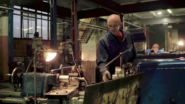 Industrial workman using professional tool for working on metalworking machine