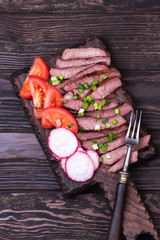 Grilled beef steak with spring onion, tomato and radish.