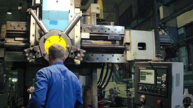 Employee using professional metalworking lathe with electronic remote control