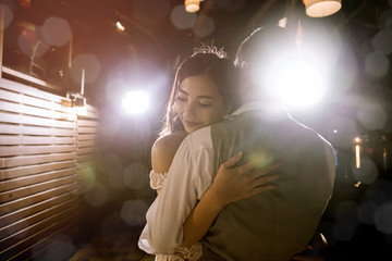 Asian woman hugging her boyfriend in night time.