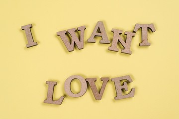 Word I want love in abstract wooden letters, yellow background.