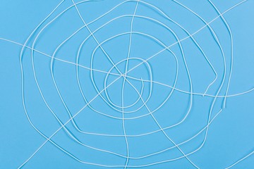 Abstract spiderweb, white threads on blue background.
