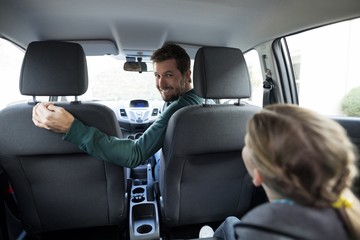 Teenage girl sitting in the back seat while woman driving a car