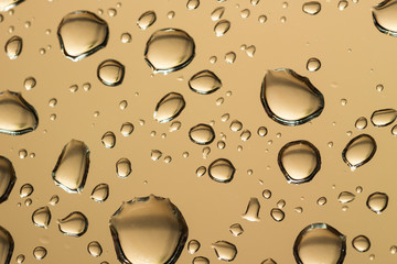 water drops on glass, a vivid image of rain drops on light brown background, colorful background texture