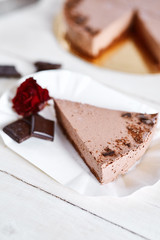 piece of Chocolate mousse cheesecake with a sprinkle of grated chocolate on a wooden table