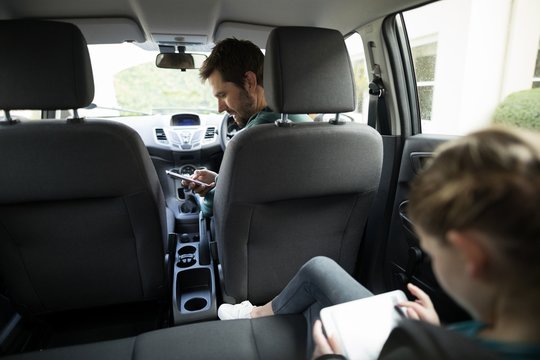Man using mobile phone in a car while teenage girl sitting in