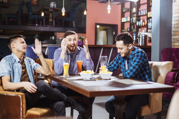 Friendship, sports and entertainment concept - happy male friends with beer watching tv at the bar.
