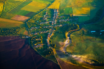 Aerial view of a small russian village with river and green fields during sunrise