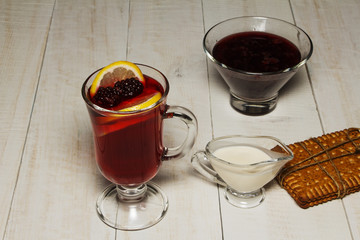Mulled wine with lemon on a wooden white table.