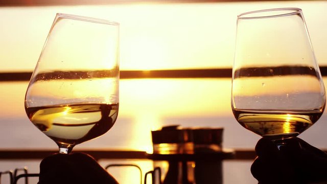 Friends drinking white wine, toasting. Clinking have party outdoors. Enjoying time together in slow motion during amazing sunset. 3840x2160