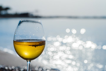 Glass of wine on sand on sea background.