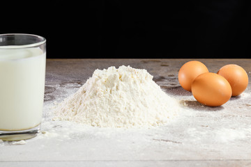 Flour and eggs, cooking dough. The recipe for cooking pizza, pasta, bread. House cooking from the chef. Dark background.