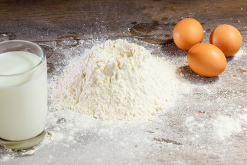 Flour and eggs, cooking dough. The recipe for cooking pizza, pasta, bread. House cooking from the chef. Wooden background.