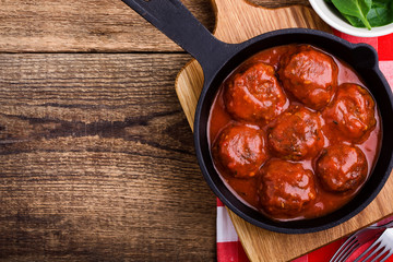 Beef meatballs in cast iron skillet on rustic wooden table
