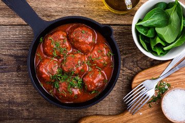 Beef meatballs in cast iron skillet on rustic wooden table