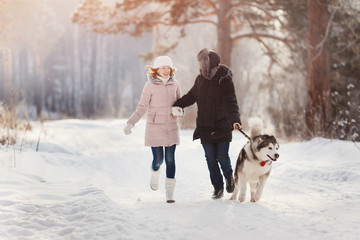 Fototapeta na wymiar Girl and man is playing, run with dog in snow, New Year's holidays, rest in nature in winter.