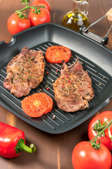 Grilled steak on grill pan with tomatoes on dark background