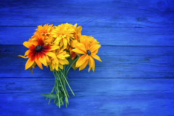 Bouquet of bright summer flowers on colorful wooden boards.