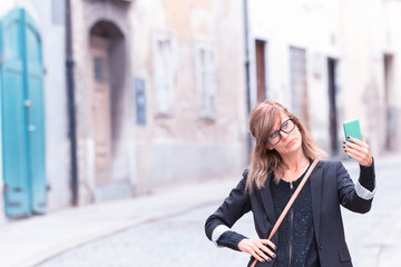 Cute woman holding cellphone in urban surroundings.