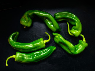 unevenly shaped green Italian peppers on dark background