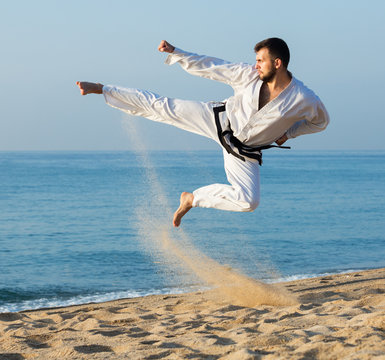 Guy practising karate at seaside