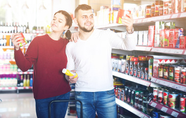 young couple choosing purchasing canned food for week at supermarket