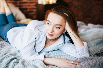 Obraz premium красивая молодая девушка в джинсах и рубашке лежит на кровати beautiful young girl in jeans and shirt lying on the bed