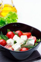 Salad with vegetables, cheese or tofu, tomatoes, herbs on white background.