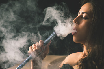Young, beautiful girl smoke a hookah at club