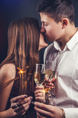 Couple kisses celebrating New Year's eve drinking champagne and lighting up sparklers