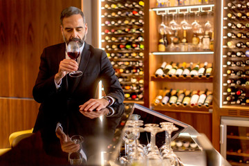 Handsome mature man tasting red wine