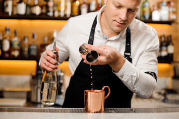 Bartender pouring a portion of alcoholic drink into the cup