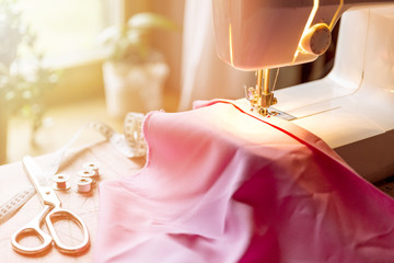 Sewing machine on table in workshop. Sewing process with scissors, measuring tape and spool