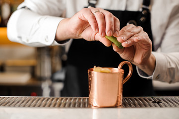 Bartender squeezing fresh lime juice into the cup