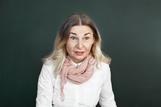 Emotional European woman pesnioner having surprised expression on her beautiful wrinkled face, expressing full disbelief and shock while talking to friend, hearing juicy gossip, posing in studio