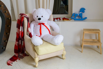 The children's place with a toy - big white bear. Interior room for a child. Cozy atmosphere inside the house by the window. 