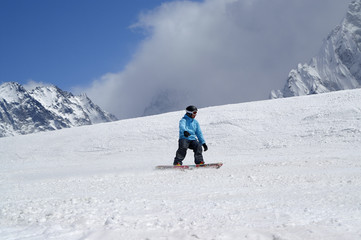 Fototapeta na wymiar Snowboarder downhill on ski slope in high snowy mountains